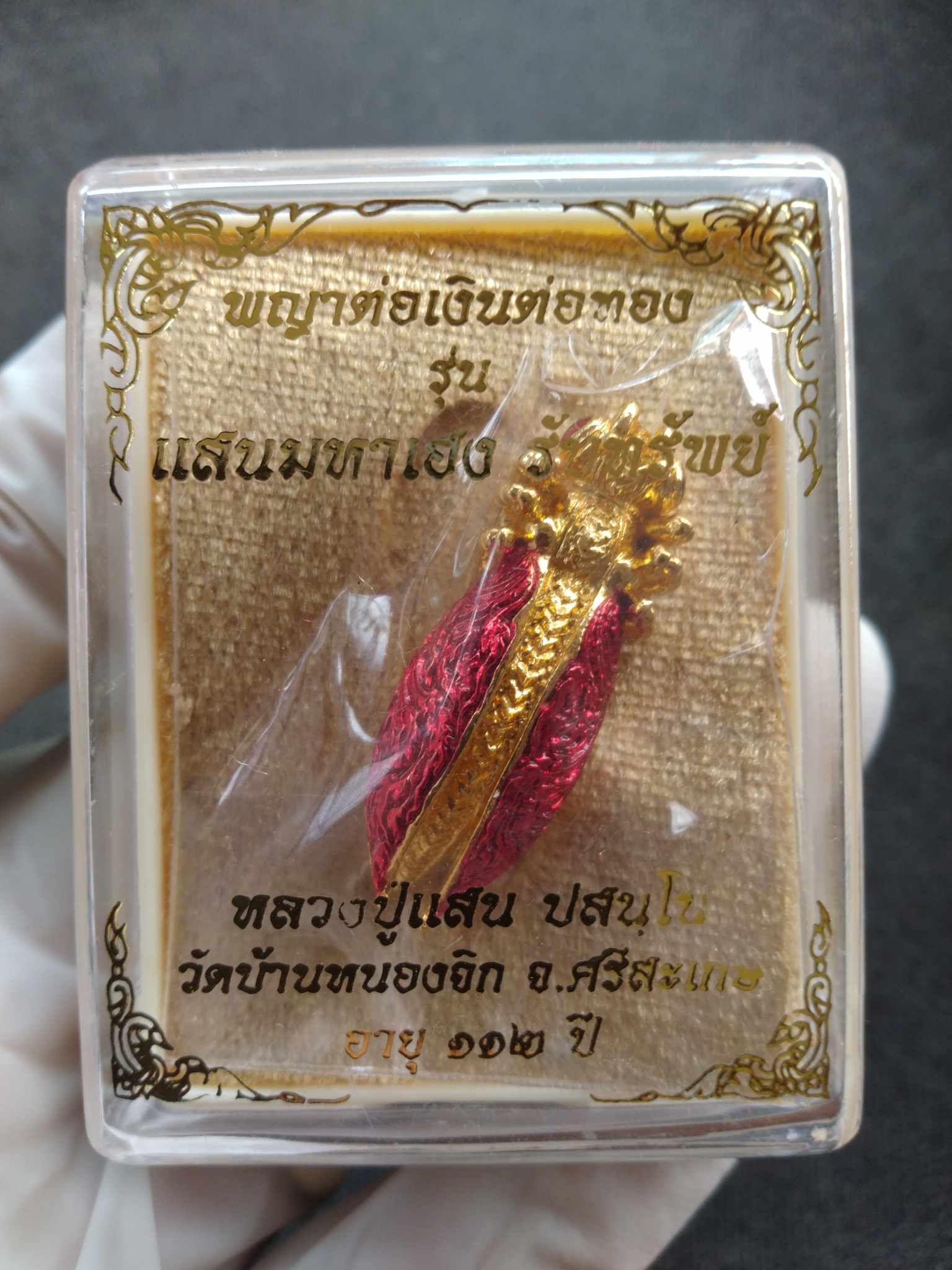Phaya Tor Ngern Tor Thong Grand Millionaire Amulet gold and red talisman in clear display box with Thai text