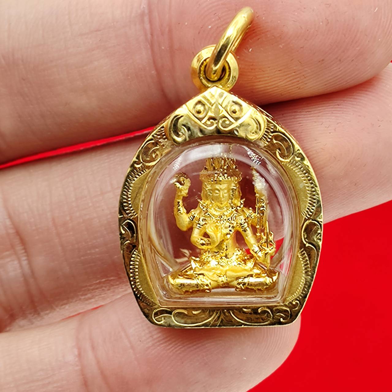 Phra Phrom amulet gold case ornate gold miniature deity in clear dome pendant held between fingers