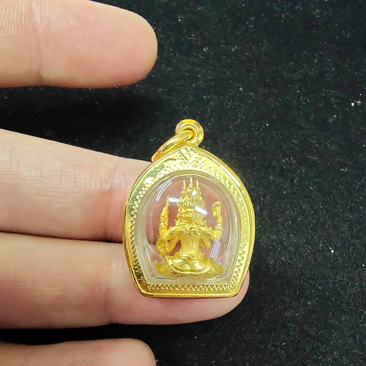 Phra Phrom amulet gold case with clear front showing seated four faced Brahma held between fingers