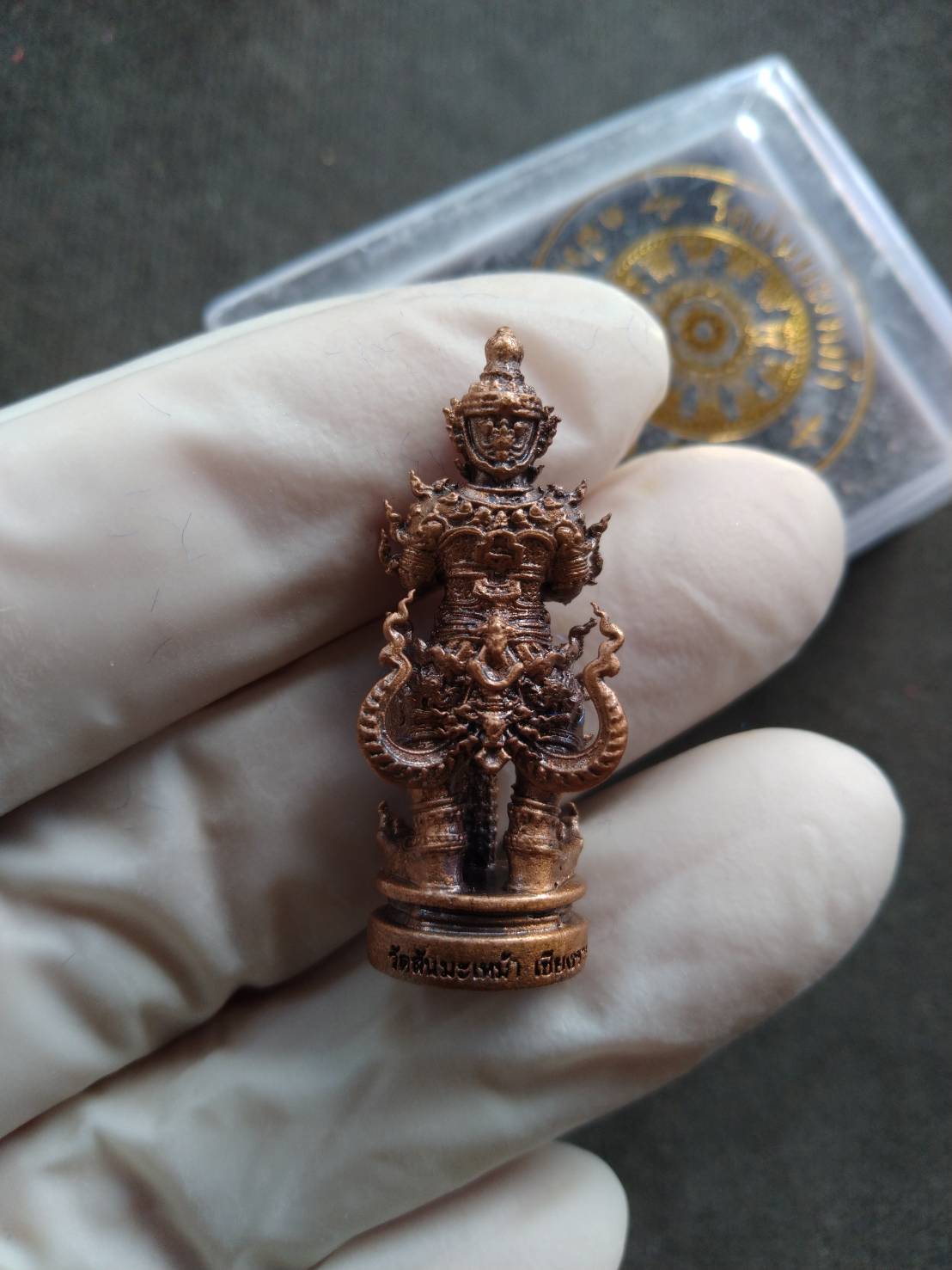 Phra Taow Wessuwan amulet for wealth bronze pendant held in gloved hand showing intricate deity details