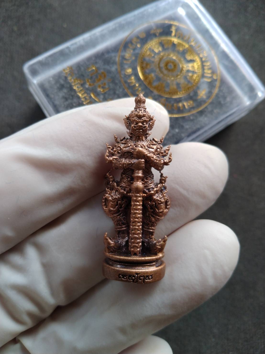Phra Taow Wessuwan amulet for wealth copper guardian pendant held in gloved hand with Thai Blessing Co case