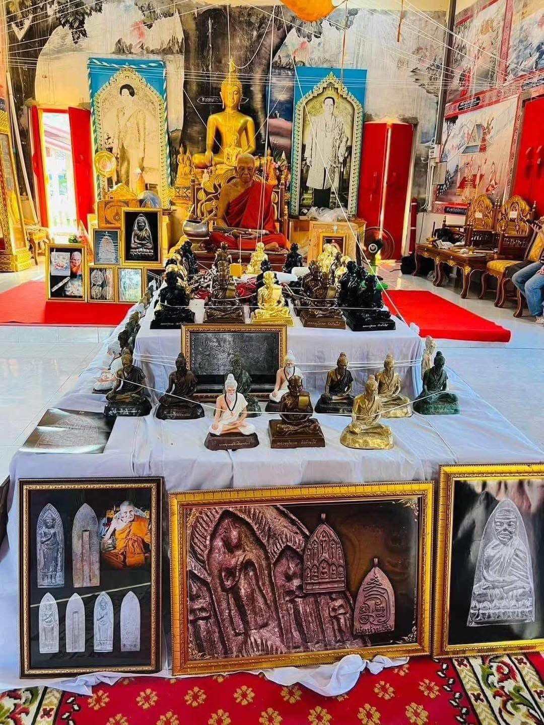 Phu Lersi Jivaka Komarabhacca statue collection displayed on temple altar with Buddha and framed reliefs