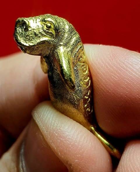 Pla Du Yong (Manatee) Amulet . Gold tone miniature Thai manatee amulet held between fingers carved details for luck and protection