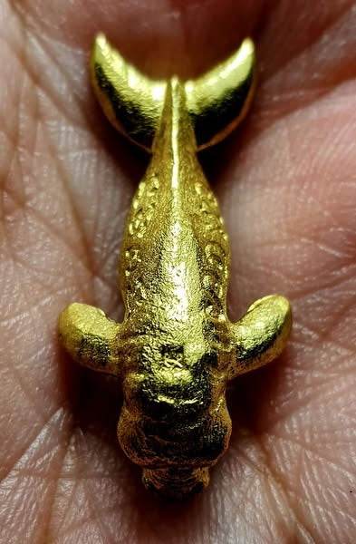 Gold Pla Du Yong (Manatee) Amulet resting in a palm, small Thai feng shui household charm for protection and luck
