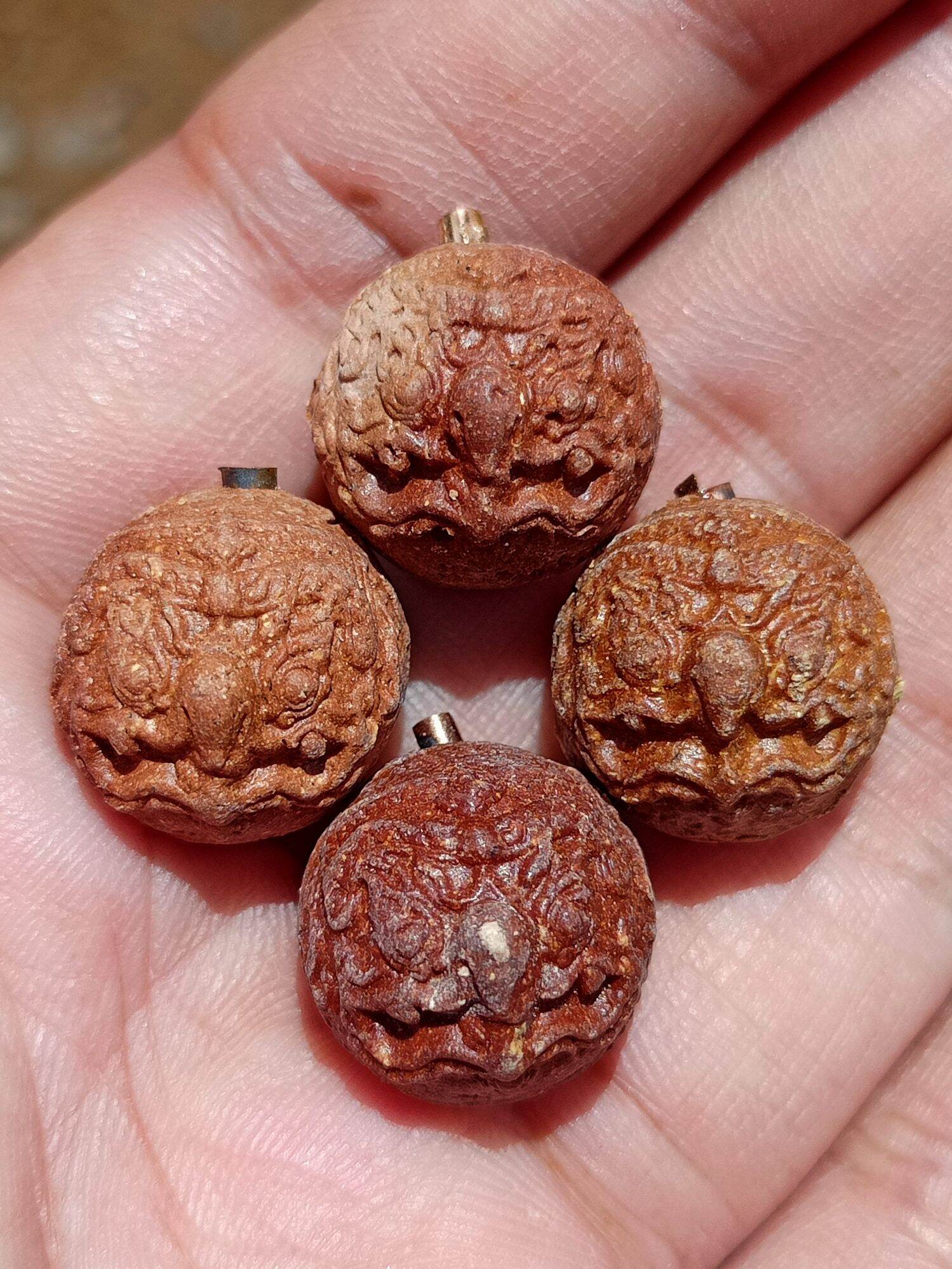 Rahu Garuda mercury talisman ball carved wooden seed pendants set of four held in palm by Thai Blessing Co