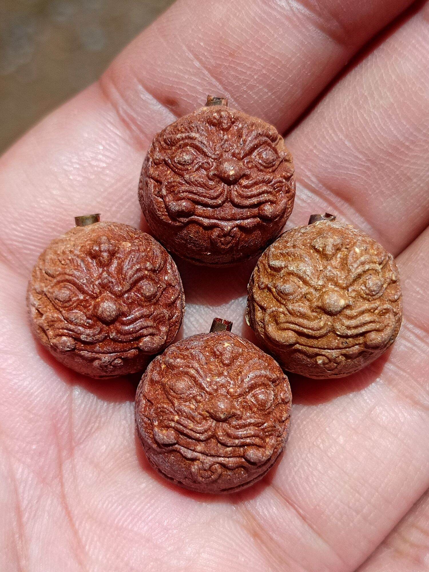Rahu Garuda mercury talisman ball carved nut pendants with fierce Garuda faces shown in palm by Thai Blessing Co