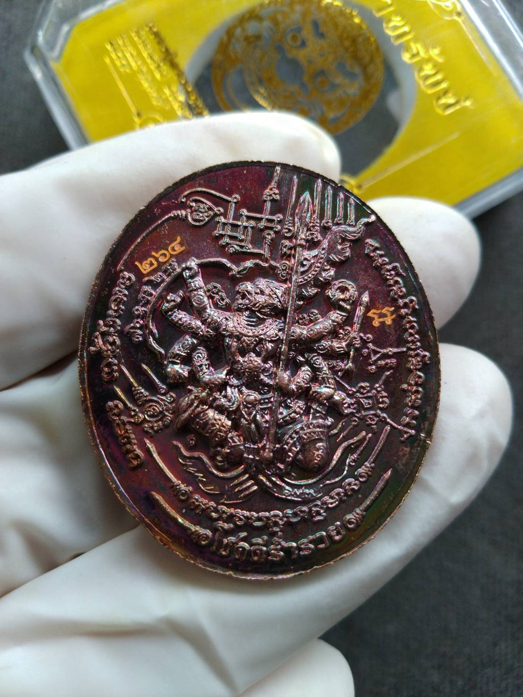 Thai Blessing Co Rahu Hanuman amulet for wealth copper oval pendant held in gloved hand