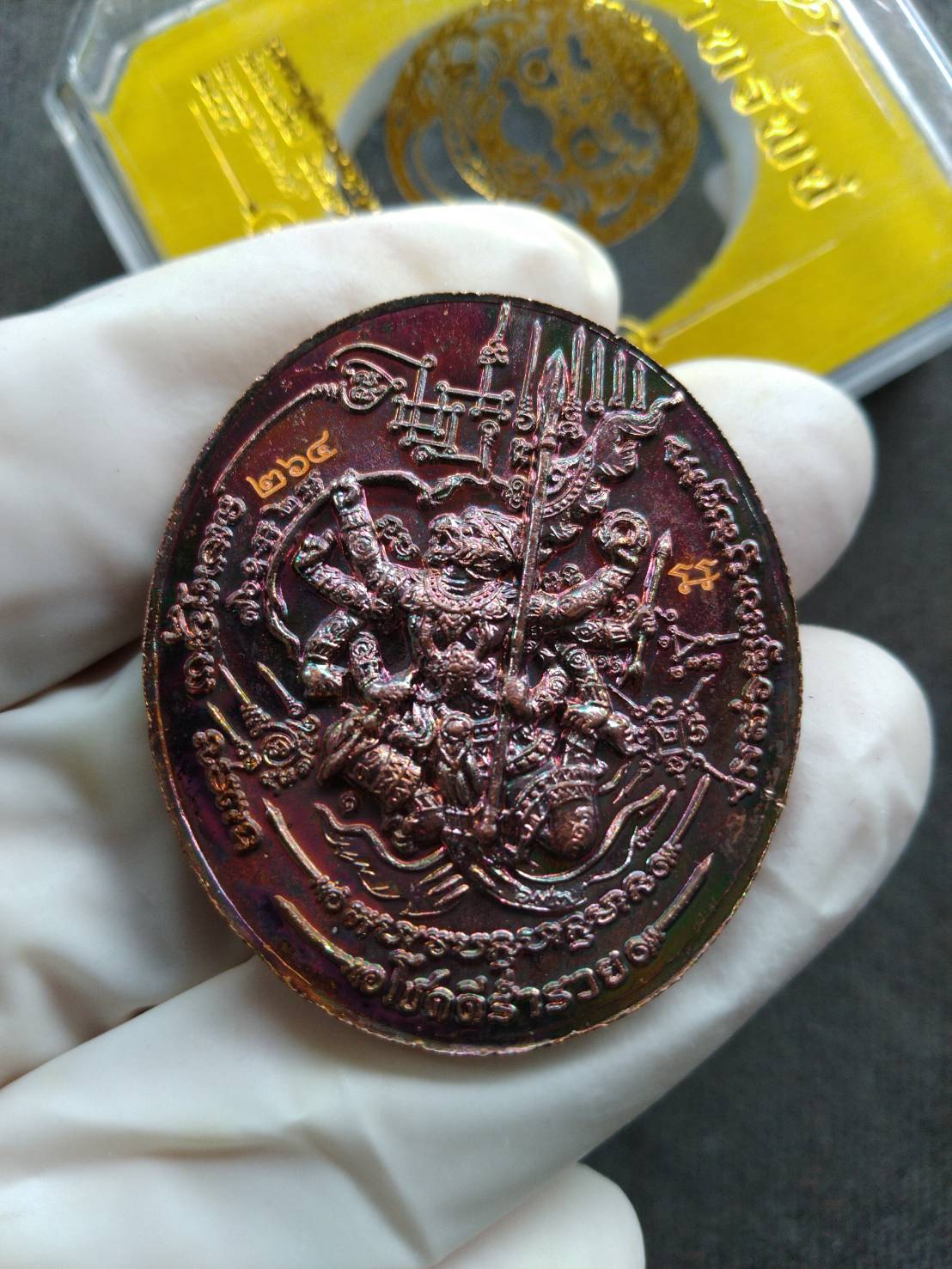 Thai Blessing Co Rahu Hanuman amulet for wealth copper oval pendant held in gloved hand