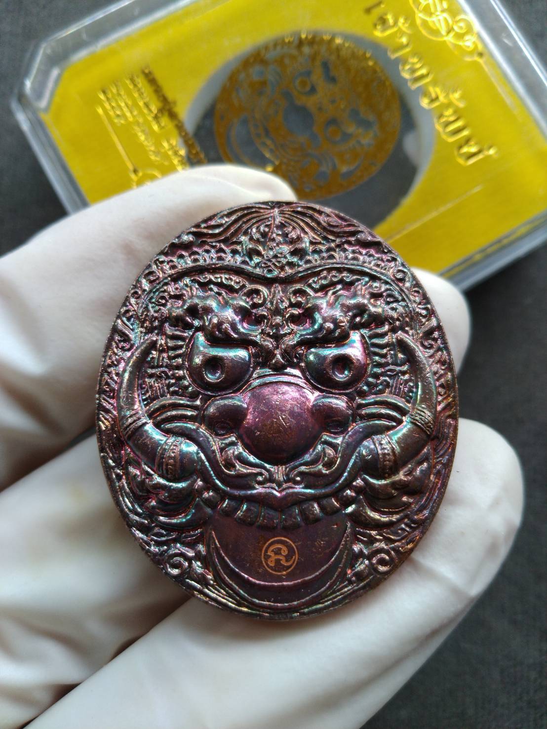 Thai Blessing Co Rahu Hanuman amulet for wealth oval metallic pendant with embossed fierce face held in gloved hand