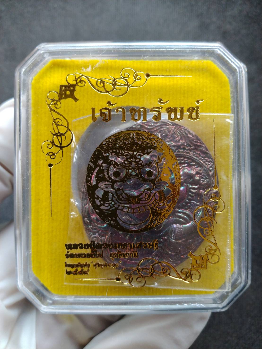 Rahu Hanuman amulet for wealth in clear plastic case with yellow backing and embossed metal pendant