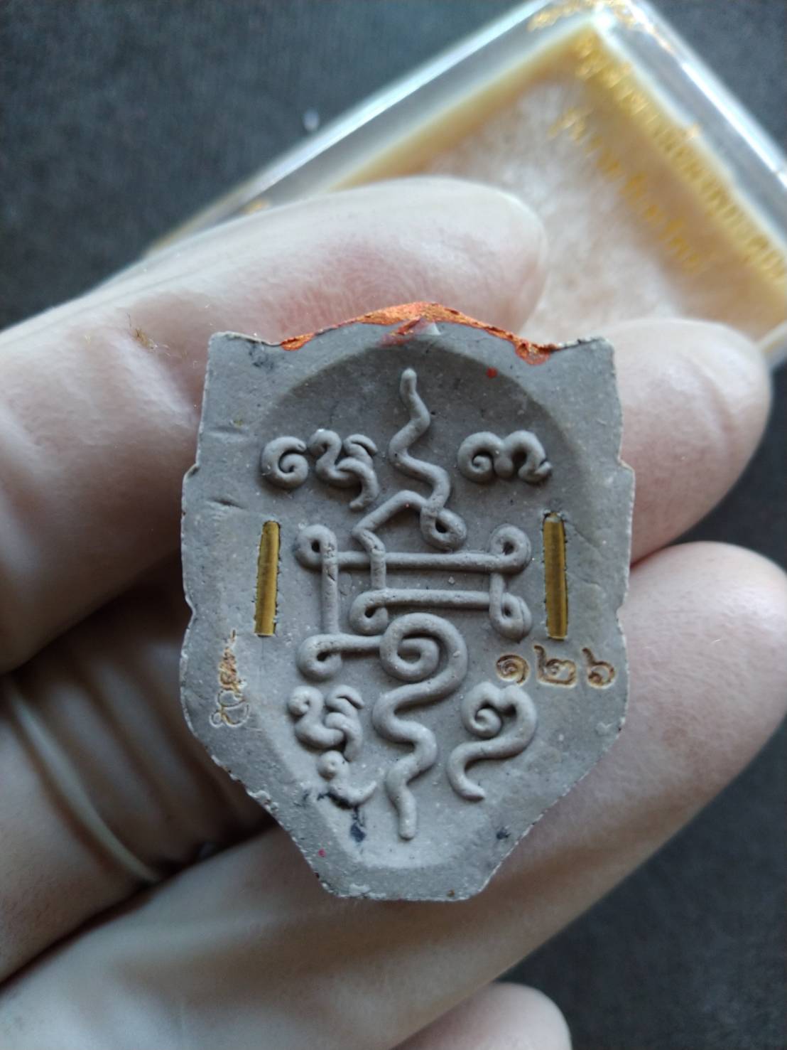 Si Hu Ha Ta prosperity charm Thai amulet pendant with sacred yantra and gold leaf details held in gloved hand