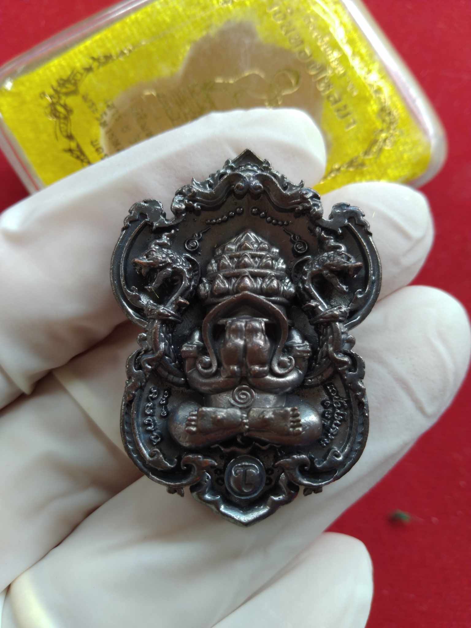 Thai Blessing Co ornate bronze Si Maharaj Phangpakal rattle amulet pendant with intricate deity carving held in glove