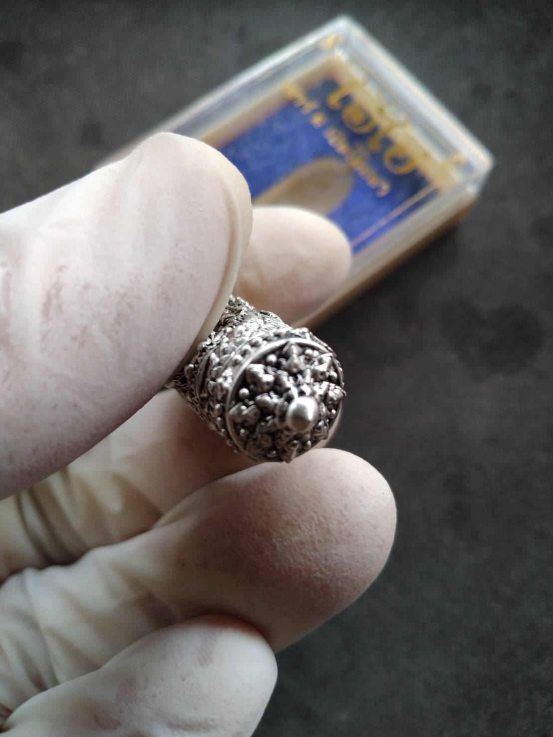 Takrud Ai Khai amulet for wealth ornate silver takrud pendant held in gloved hand with display box