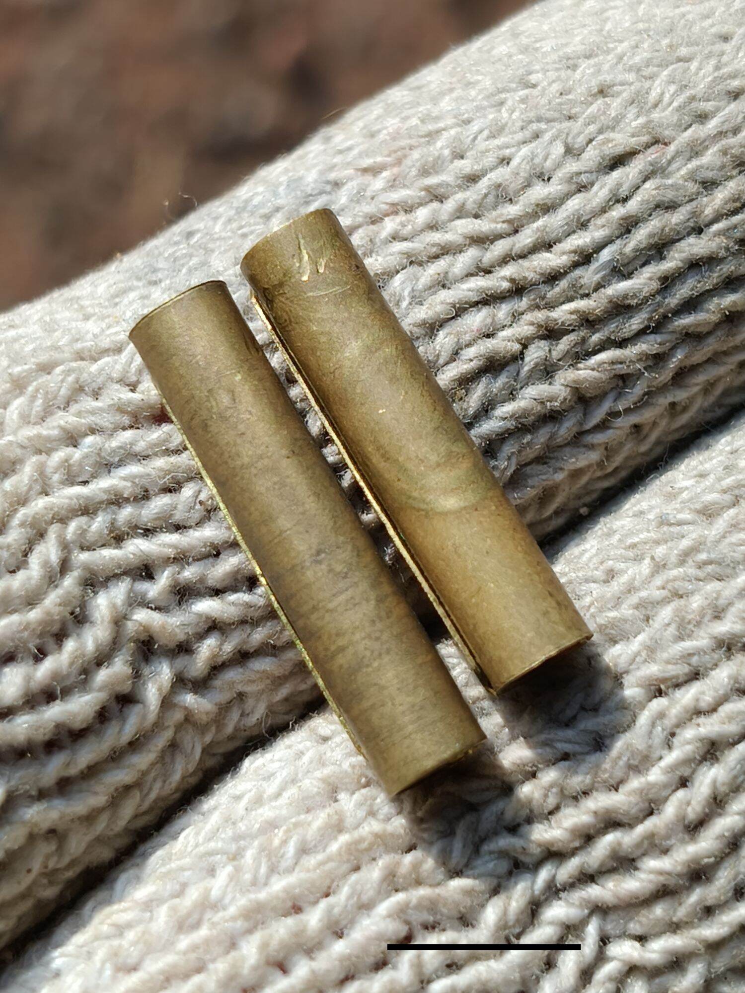 Takrud amulet for protection brass cylinder pair on knitted glove showing size and aged patina