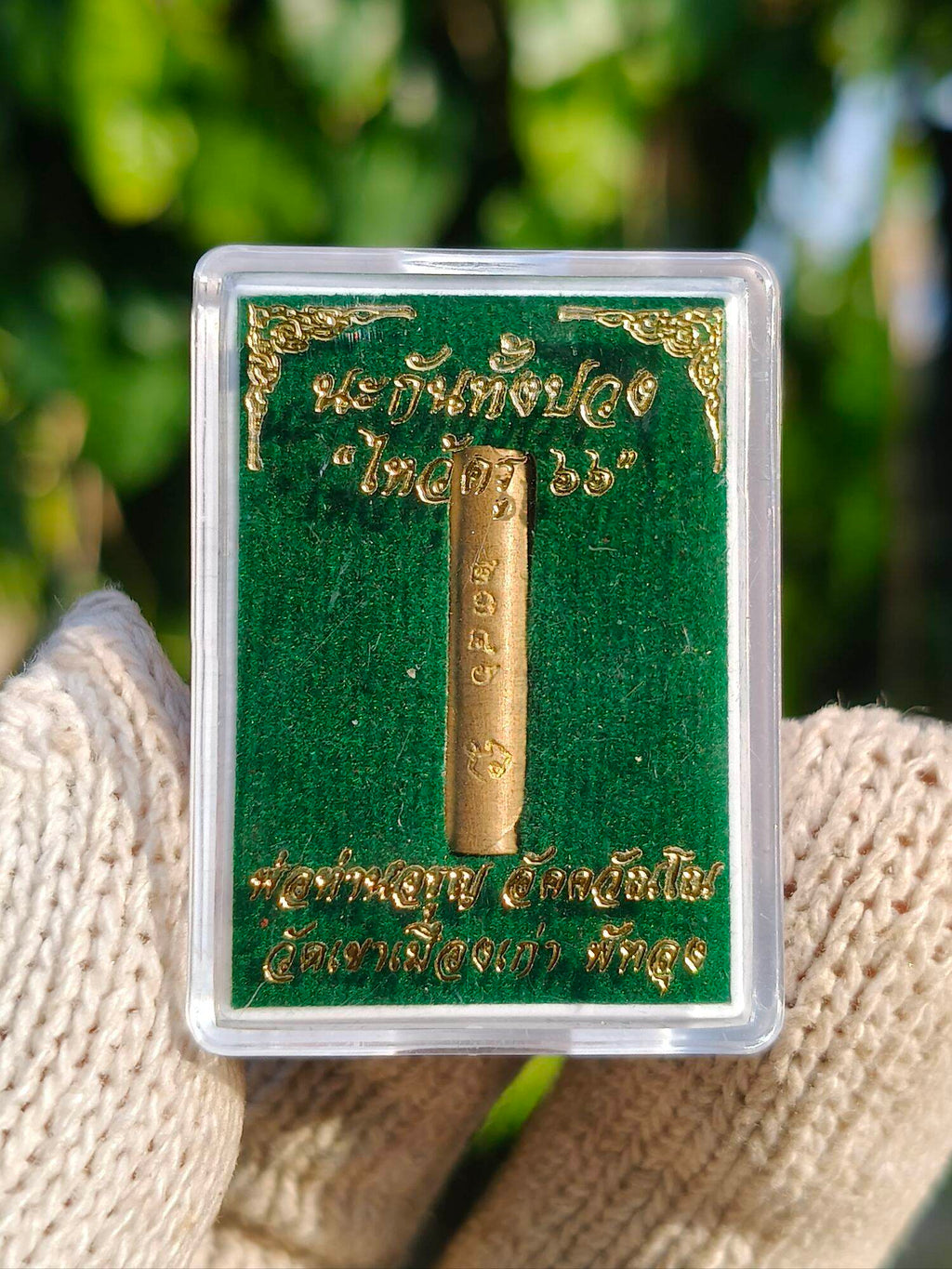Takrud amulet for protection. Gold cylinder in clear display case on green velvet backing by Thai Blessing Co