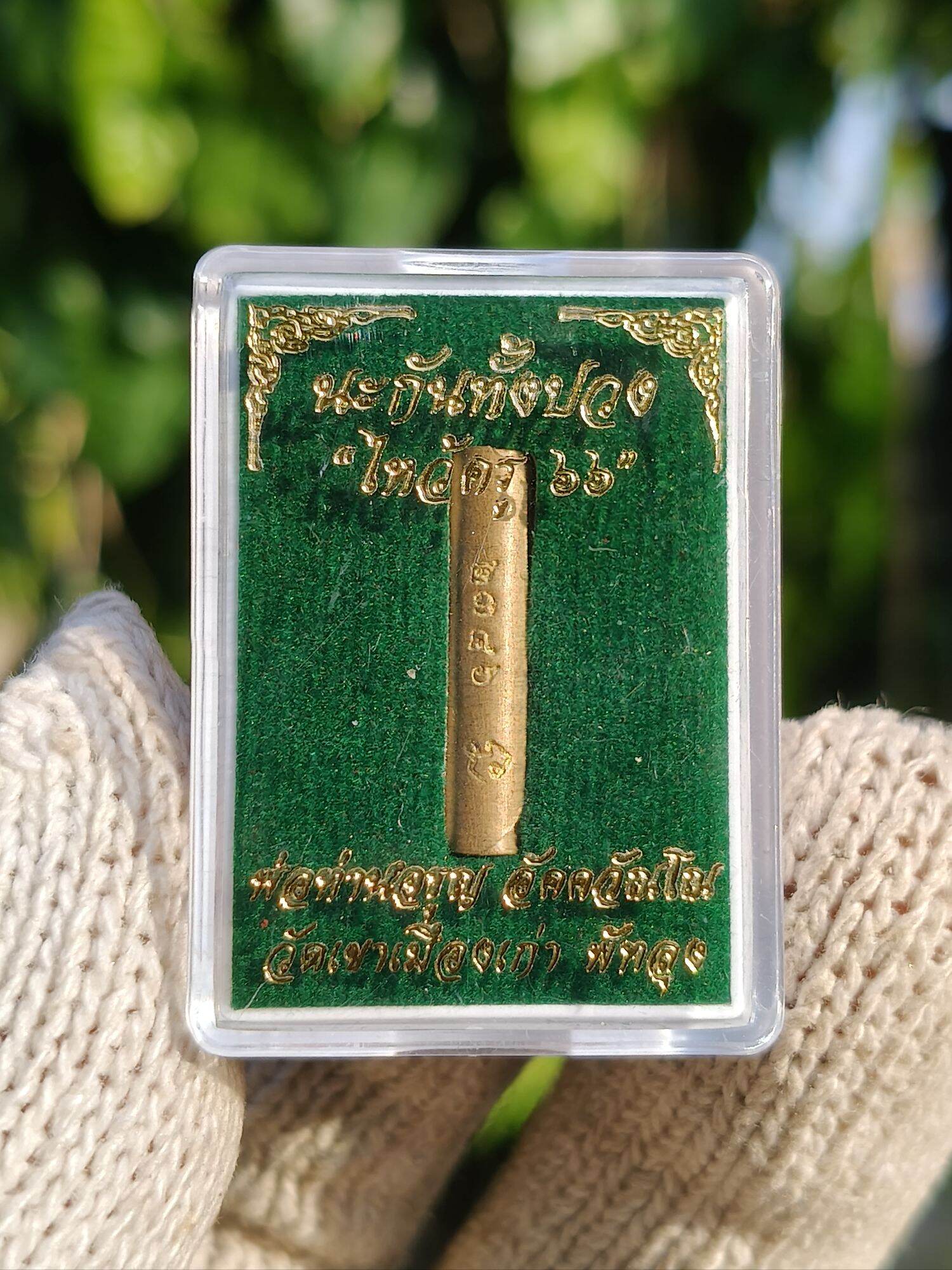 Takrud amulet for protection. Gold cylinder in clear display case on green velvet backing by Thai Blessing Co