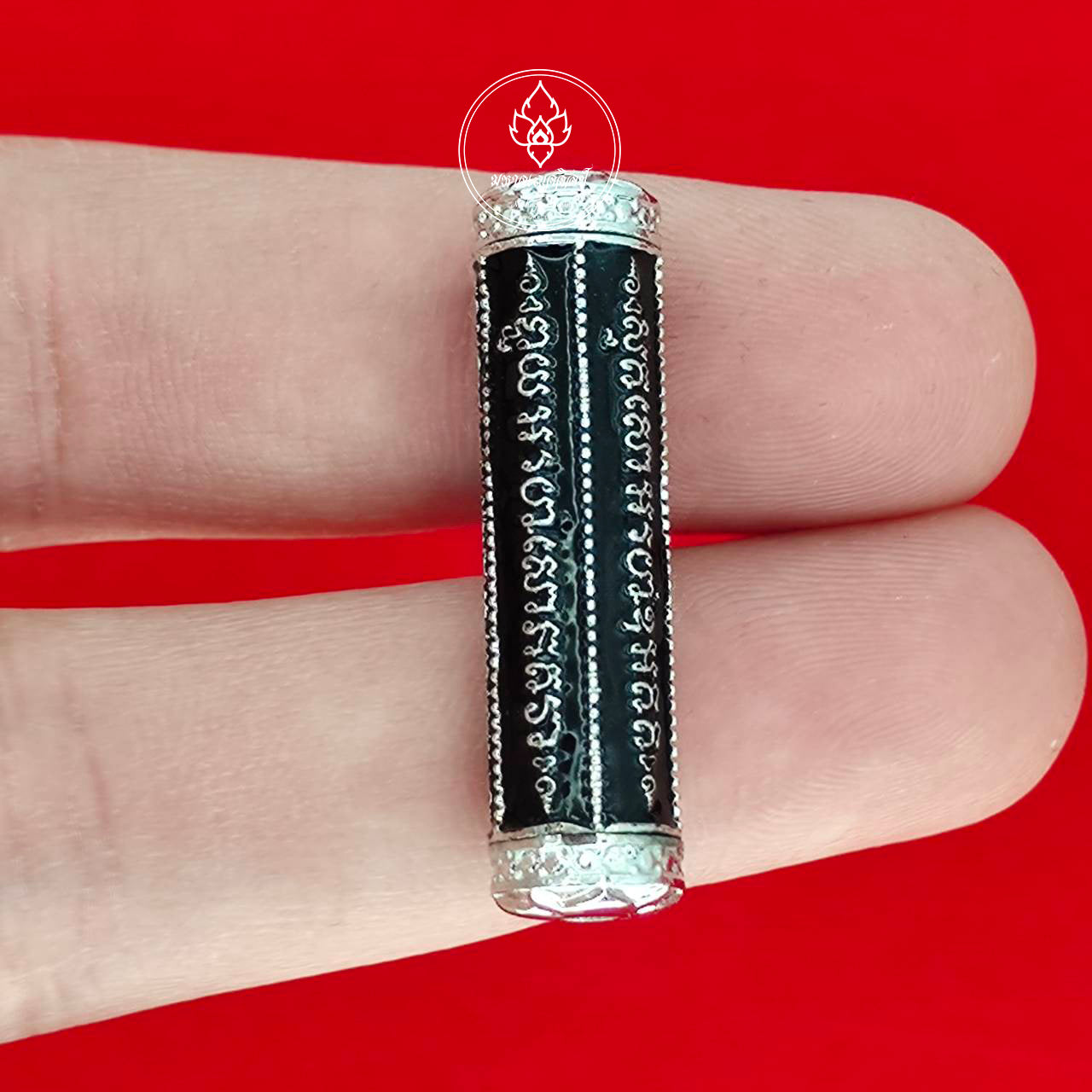 Thai Blessing Co takrut 5 lines amulet black cylindrical tube with silver end caps engraved script held on fingertips