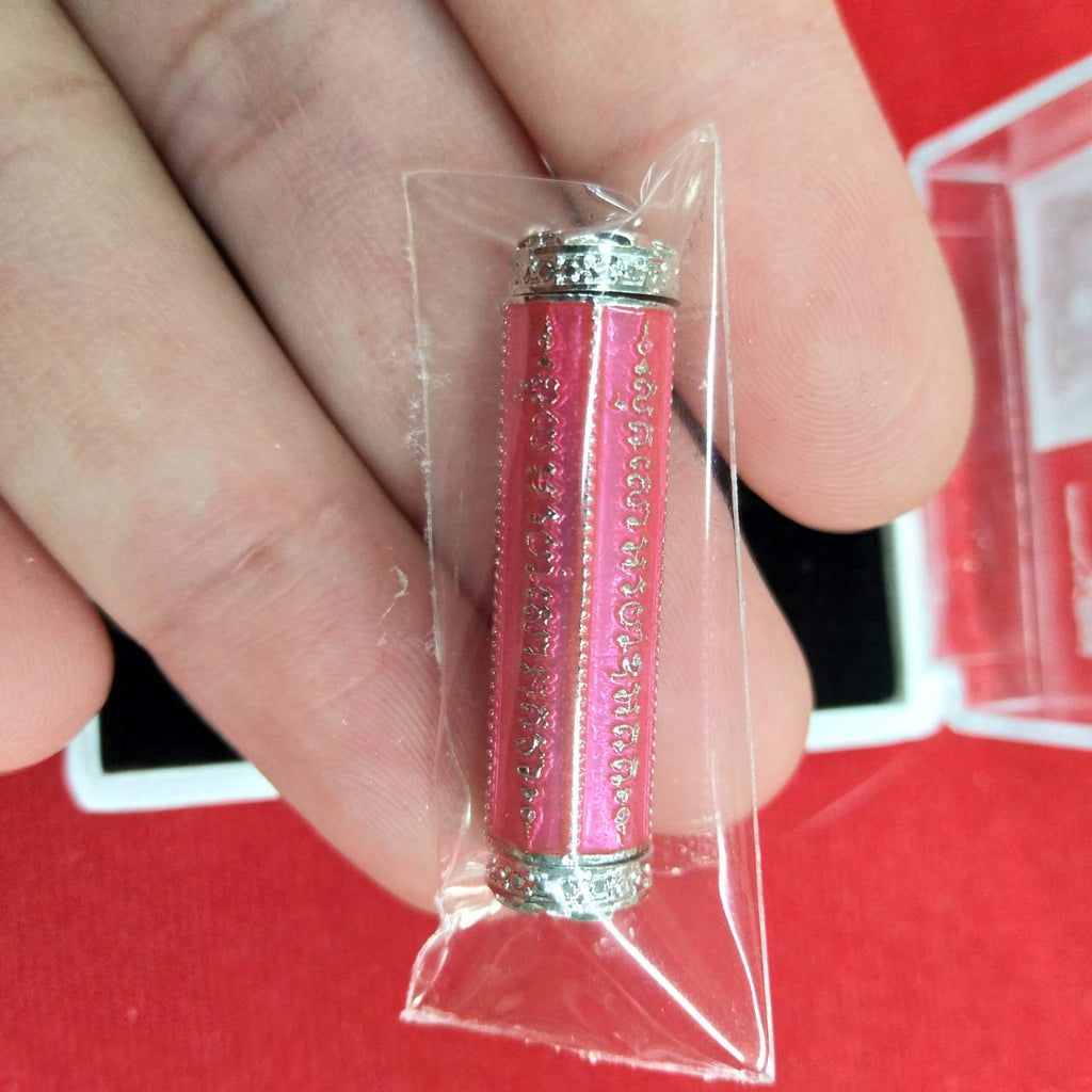Close up of pink takrut 5 lines amulet with silver end caps in plastic pouch held between fingers