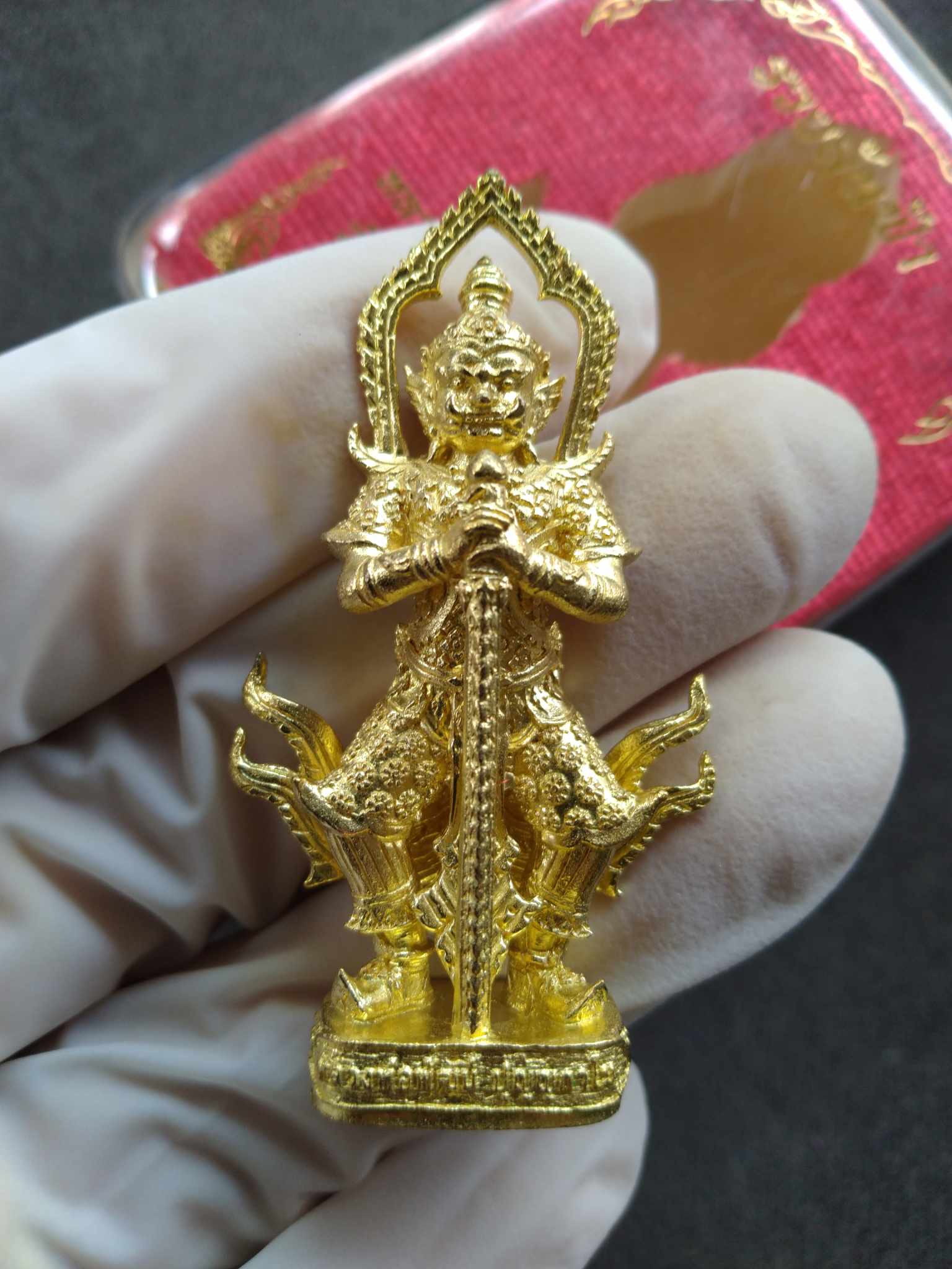 Taow Wessuwan amulet for protection gold pendant with intricate guardian deity design held in a gloved hand