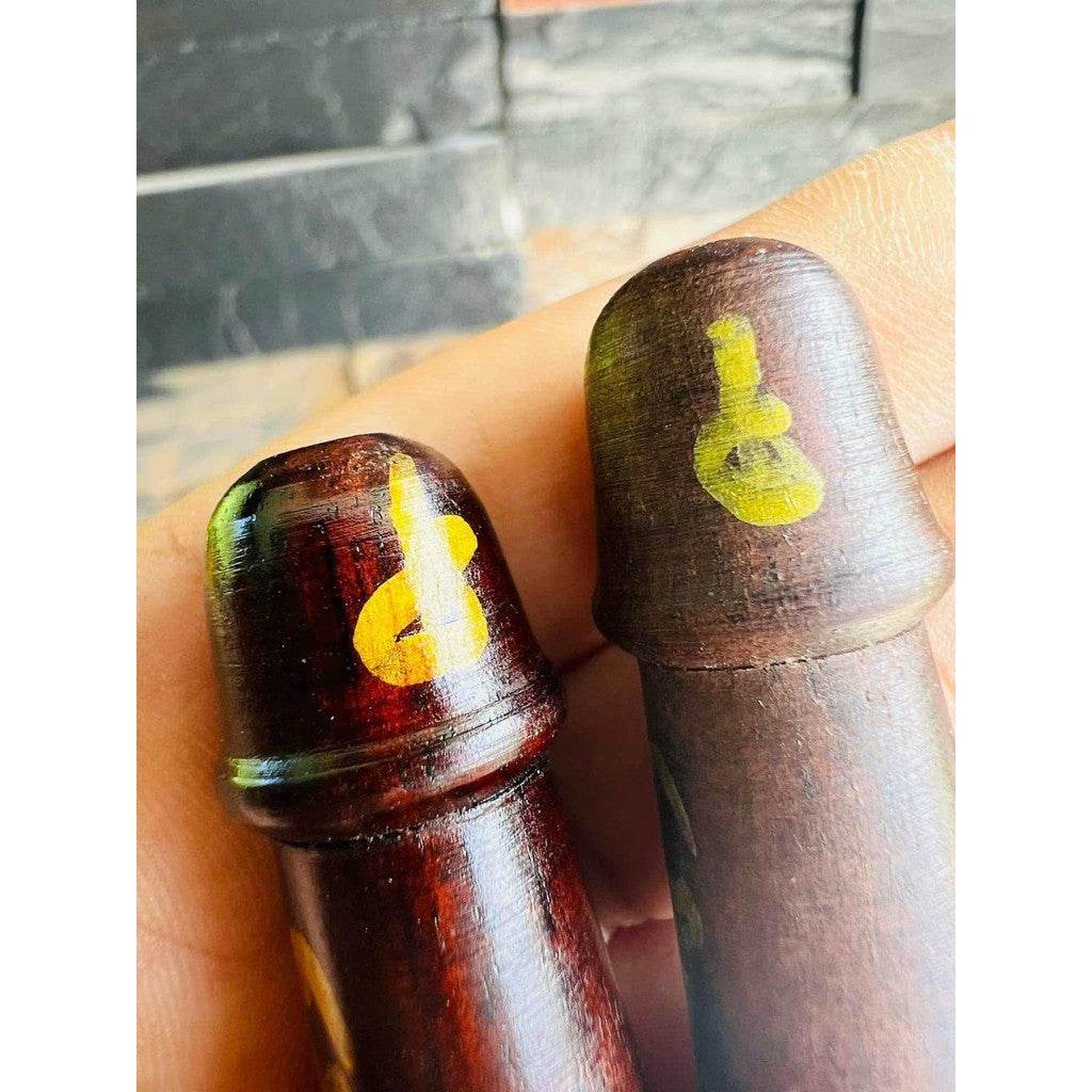 Two wooden amulets with yellow painted sacred symbols held in hand Thai charm and fortune talisman