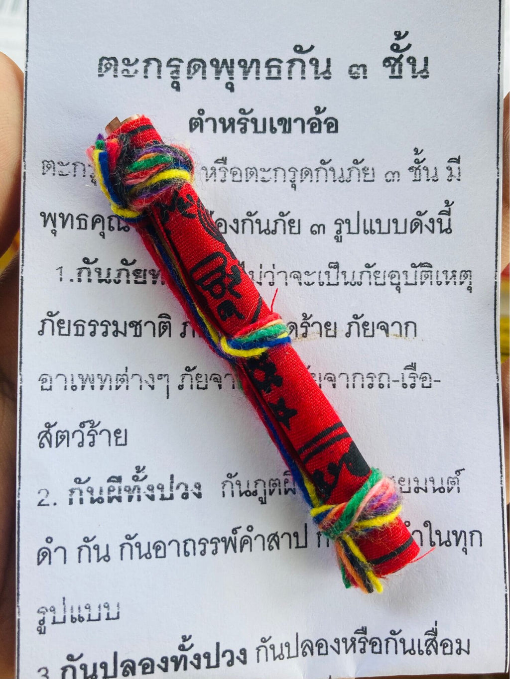 Triple-layer Phuttha Takrud amulet red cloth roll with multicolor tassels on Thai blessing paper