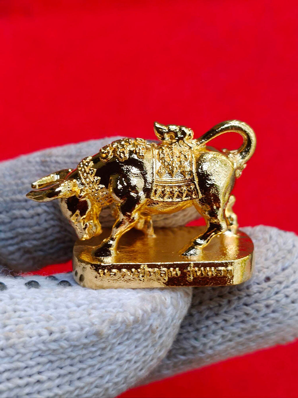 Wua Ta Nhoo sacred bull talisman gold plated amulet on gloved hand ornate saddle pedestal Thai script