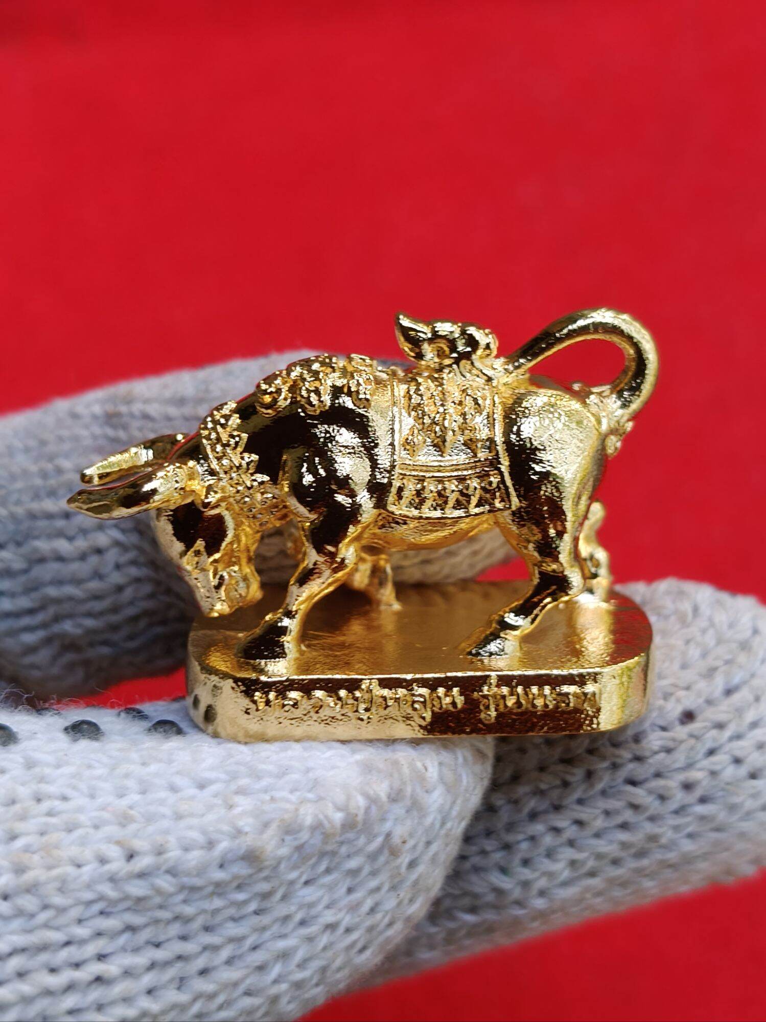 Wua Ta Nhoo sacred bull talisman gold plated amulet on gloved hand ornate saddle pedestal Thai script
