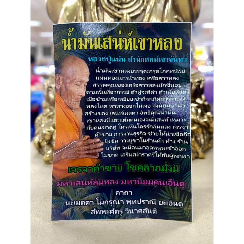 Khao Long Charm Oil for prosperity Thai blessing bottle packaging with monk image and gold statue background