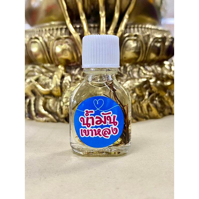 Small glass bottle of Khao Long Charm Oil for prosperity with gold leaf and herbs Thai blessing