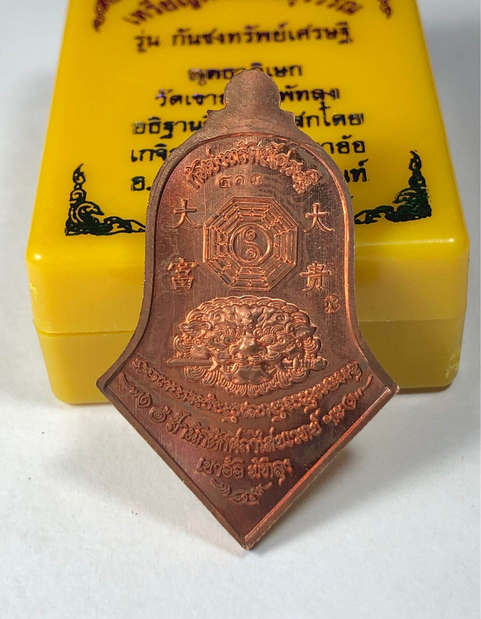 Copper Phaya Wes Suwan coin amulet pendant with bagua symbol and guardian lion on yellow box