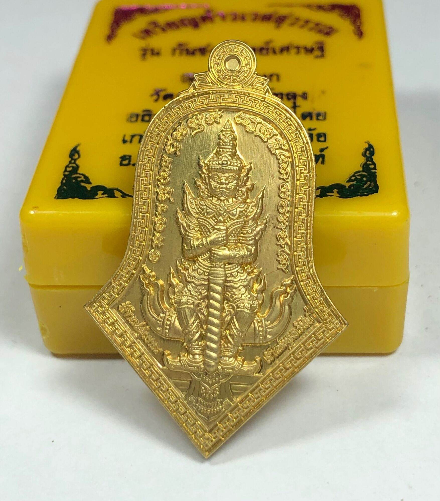 Gold Phaya Wes Suwan coin amulet pendant showing detailed Thai guardian giant design on yellow box