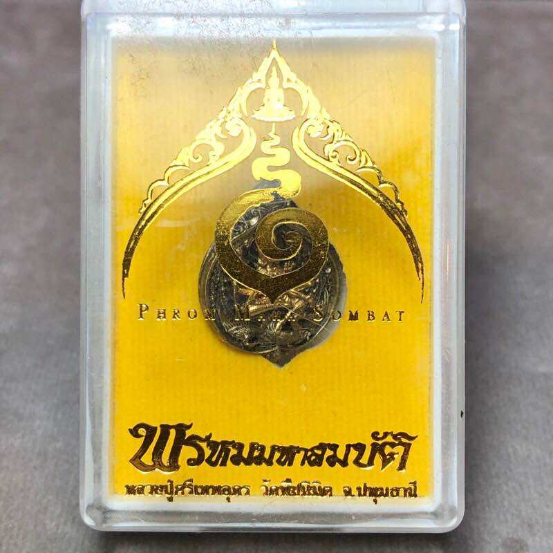 Phra Phrom Mahasombat blessed amulet metal medallion in clear plastic display case with gold backing and Thai script
