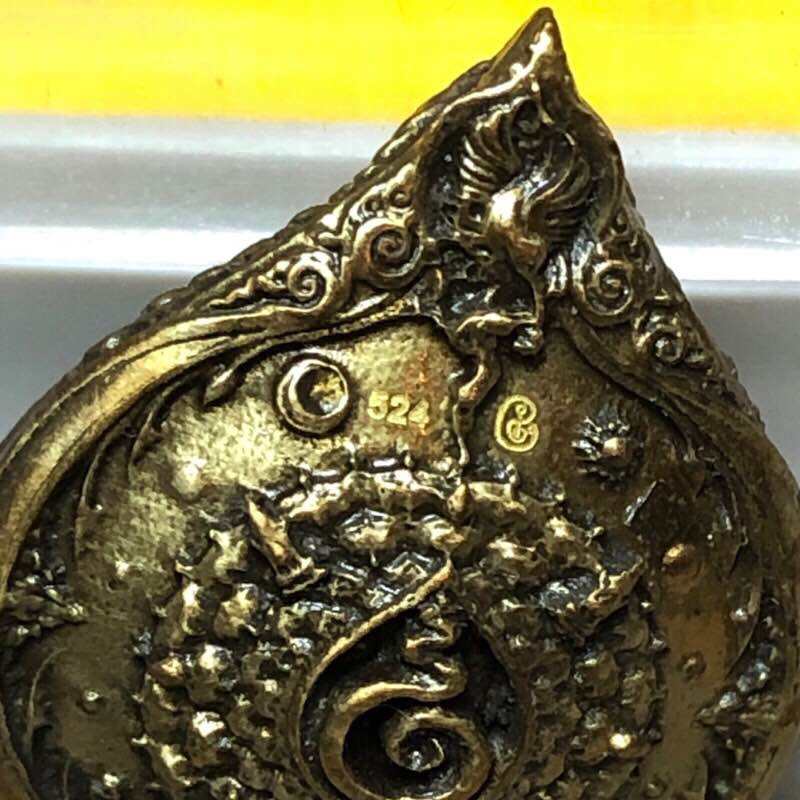 Close up of ornate gold bronze Phra Phrom Mahasombat blessed amulet with intricate Thai floral and mythical motifs