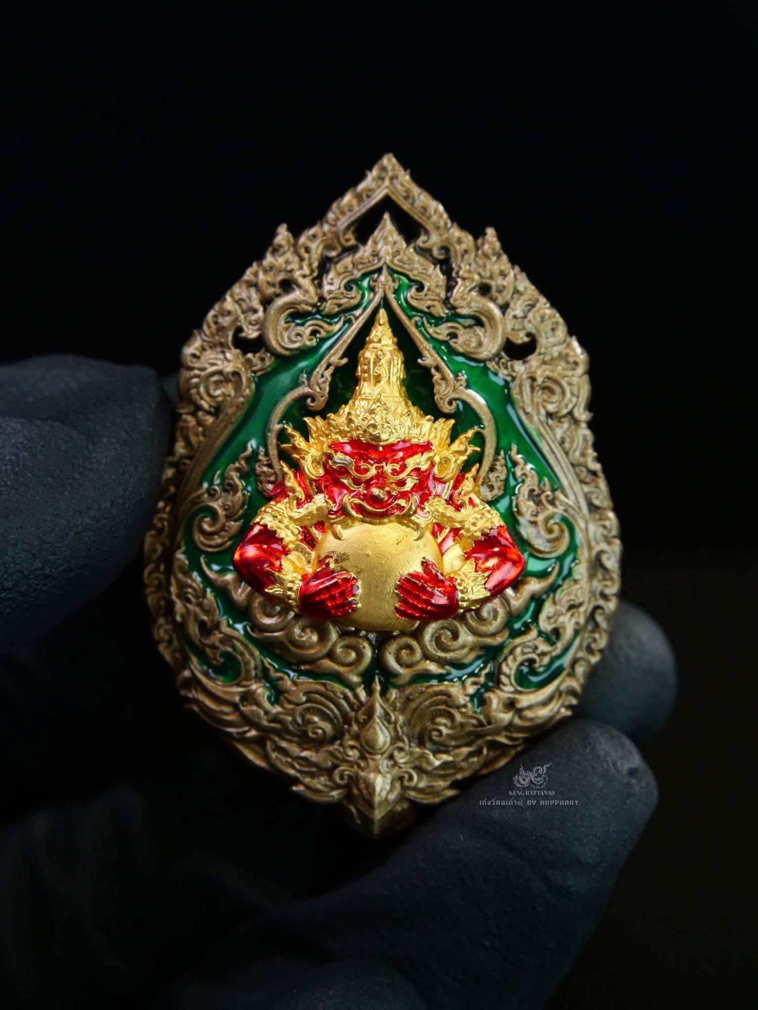 Narayana on Garuda Medallion ornate Thai amulet in gold red and green with detailed filigree held in gloved hand