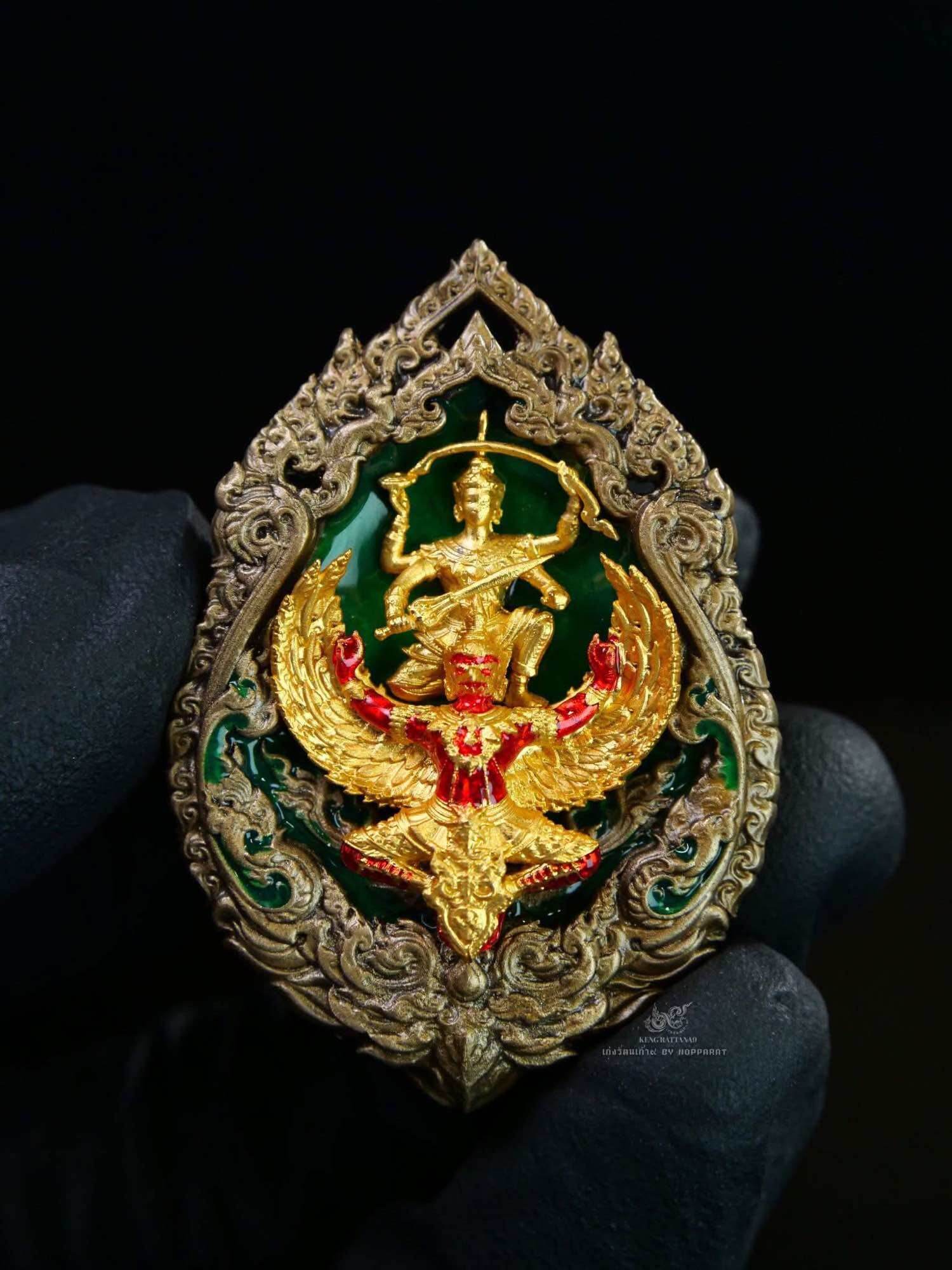 Ornate Thai amulet Narayana on Garuda Medallion gold and red enamel figure on green background
