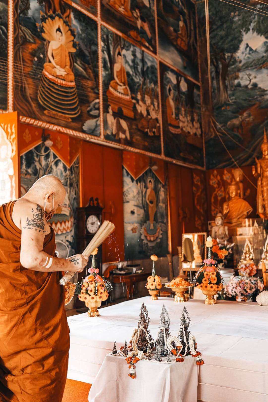 Monk blessing Thao Wessuwan statue for wealth and protection. Thai temple display of amulets by Thai Blessing Co
