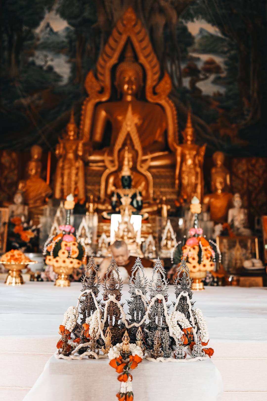 Thai Blessing Co Thao Wessuwan statue for wealth and protection. Arranged with garlands before a temple Buddha