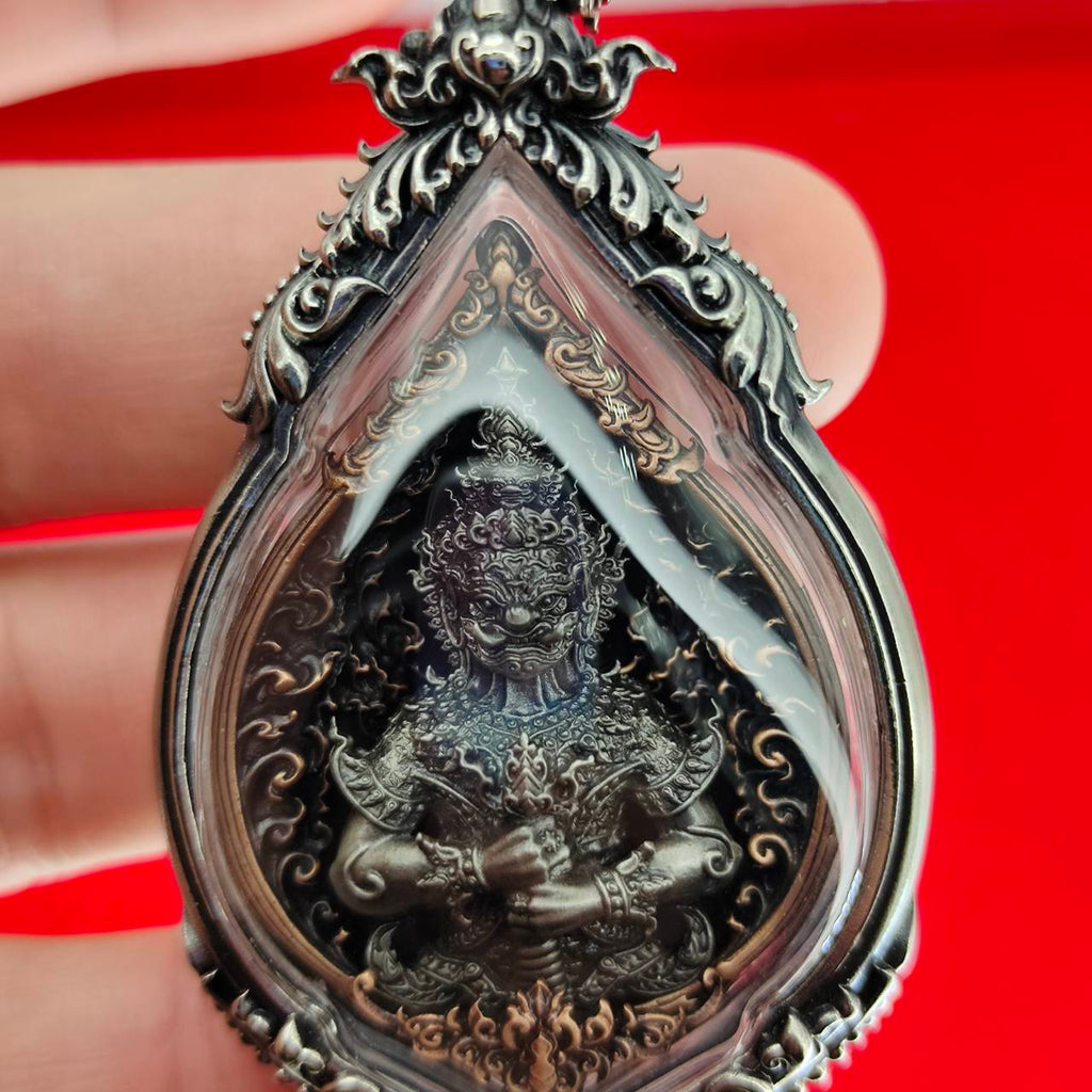 Lord Vesuvananno amulet for wealth and protection. Ornate silver teardrop pendant with dark guardian deity figure