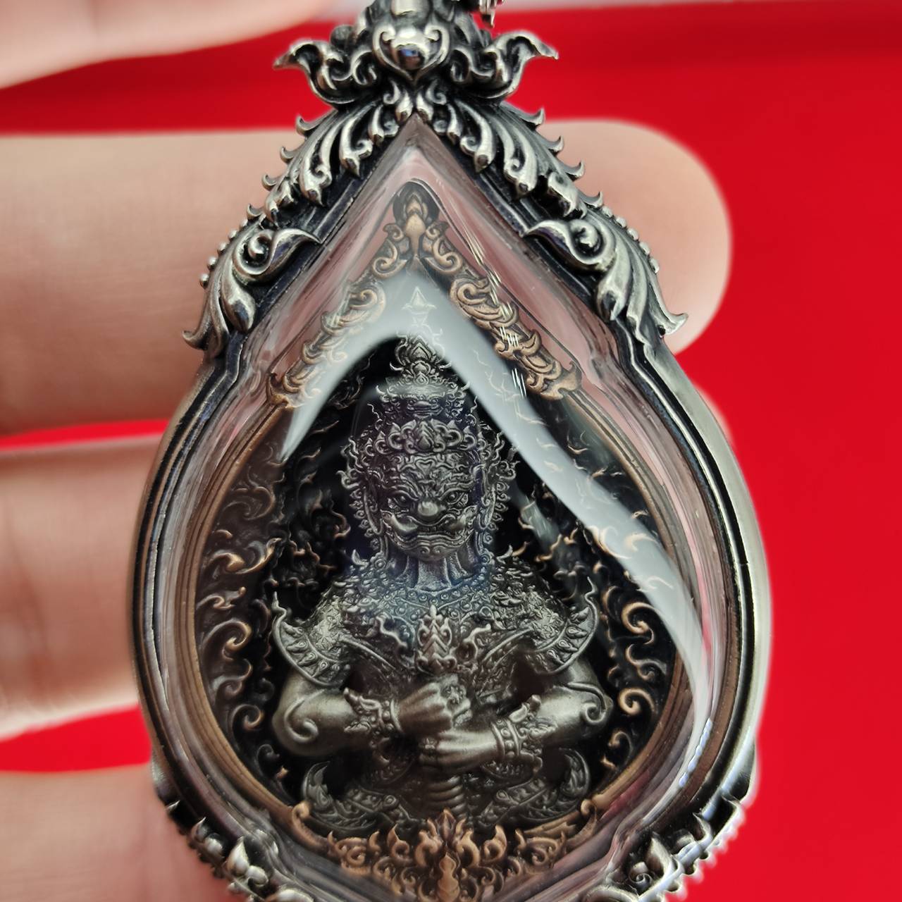 Lord Vesuvananno amulet for wealth and protection. Ornate silver teardrop pendant with dark guardian deity figure