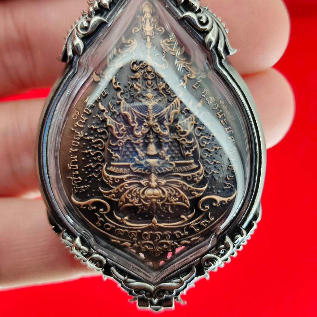 Thai Blessing Co handheld silver framed Lord Vesuvananno amulet for wealth and protection. Intricate bronze deity carving