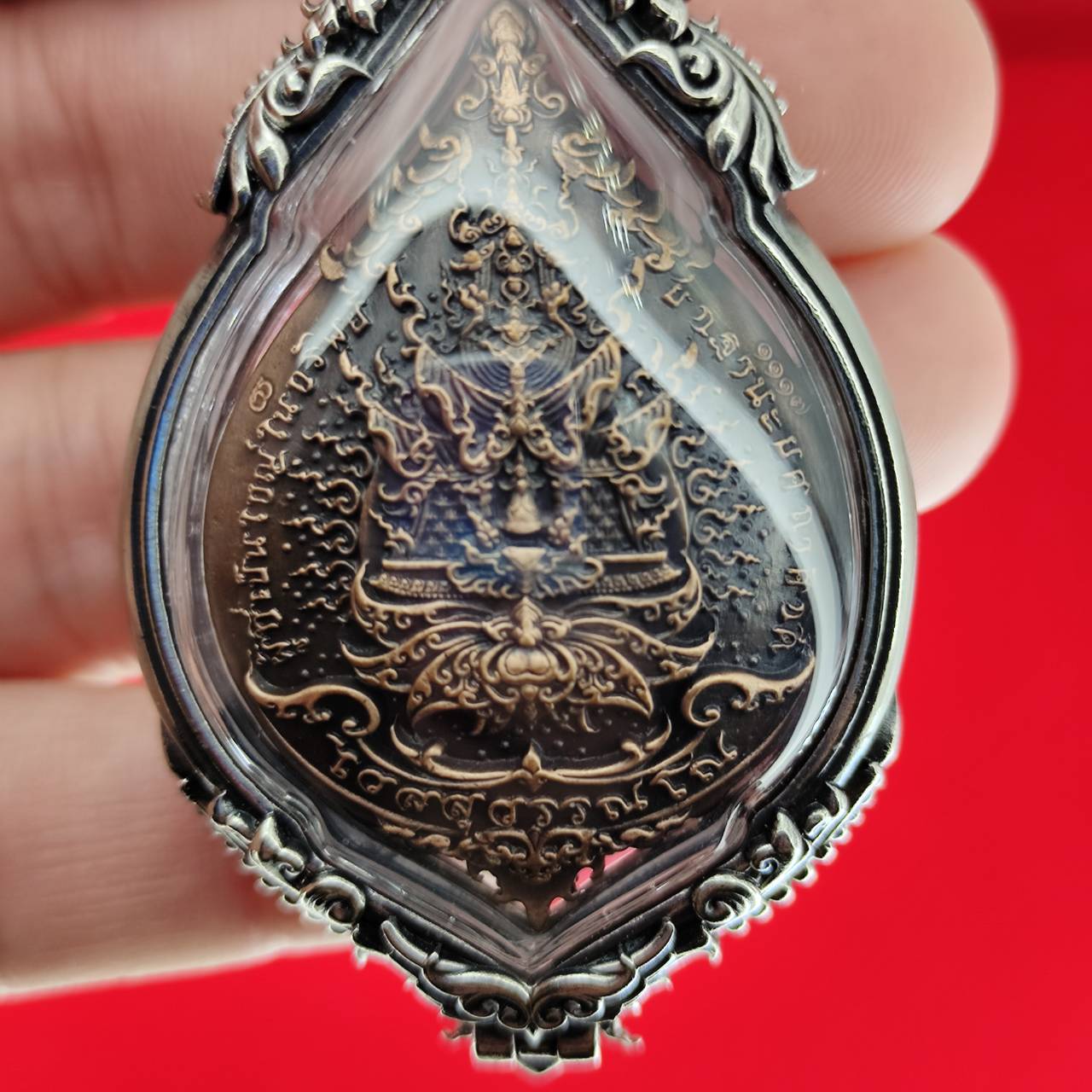 Thai Blessing Co handheld silver framed Lord Vesuvananno amulet for wealth and protection. Intricate bronze deity carving