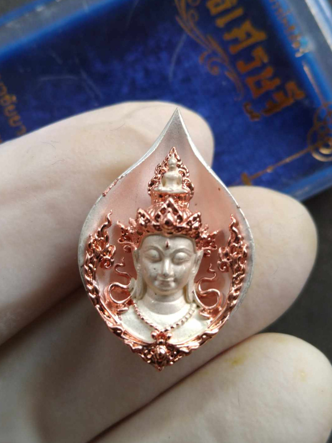 Handheld intricately detailed metal Avalokiteshvara amulet from Thailand teardrop pendant with ornate halo