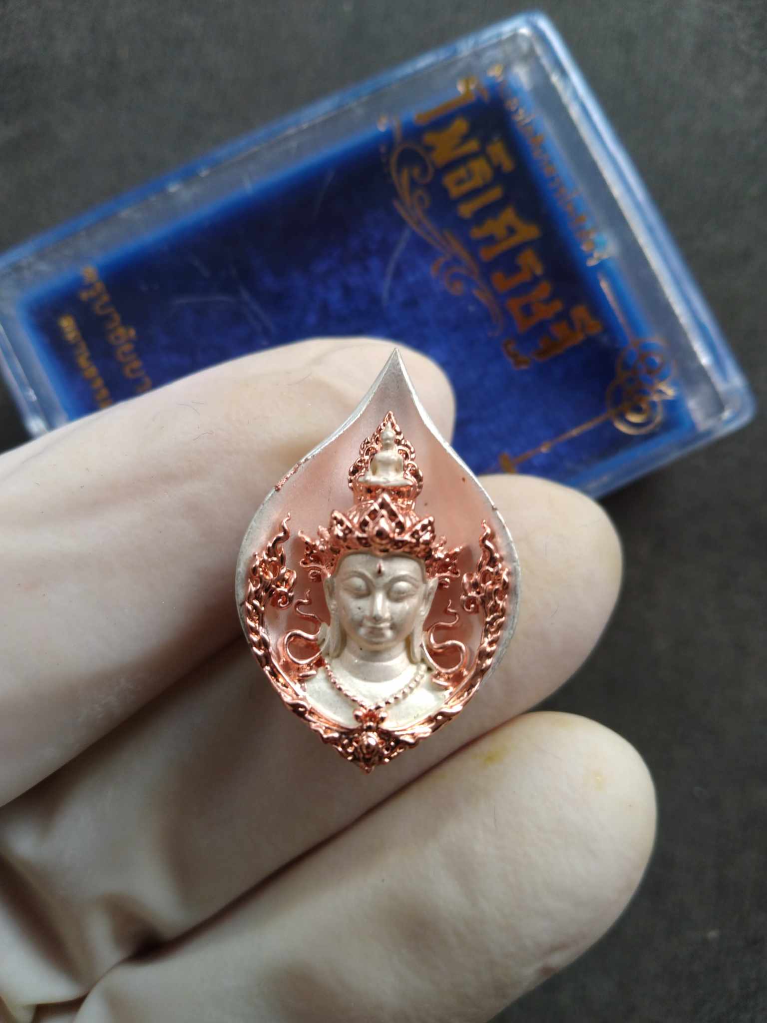 Avalokiteshvara amulet from Thailand two tone copper and silver devotional pendant held by gloved hand