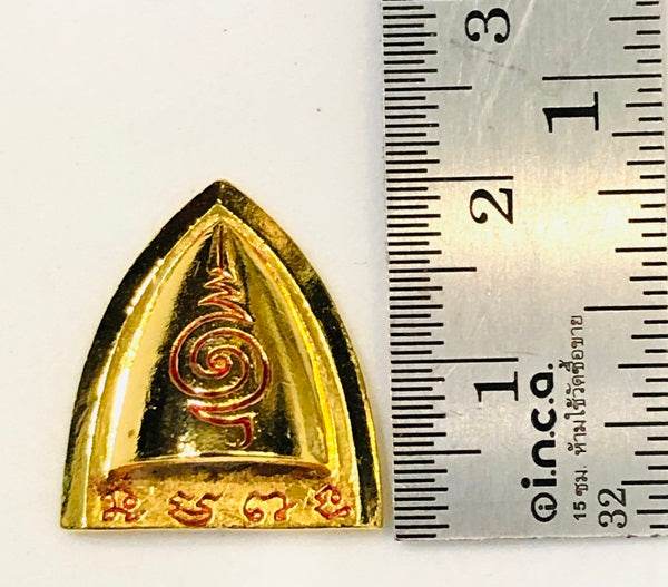 Thai blessed talisman good luck in gold color with intricate designs and ruler for size reference