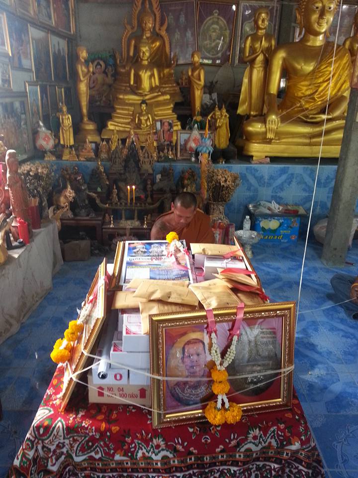 Phra Ajarn Tee Lek sacred locket displayed at a temple altar surrounded by religious artifacts