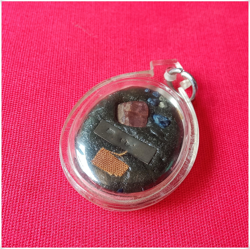Phra Ajarn Tee Lek sacred locket featuring various mystical elements in a clear casing