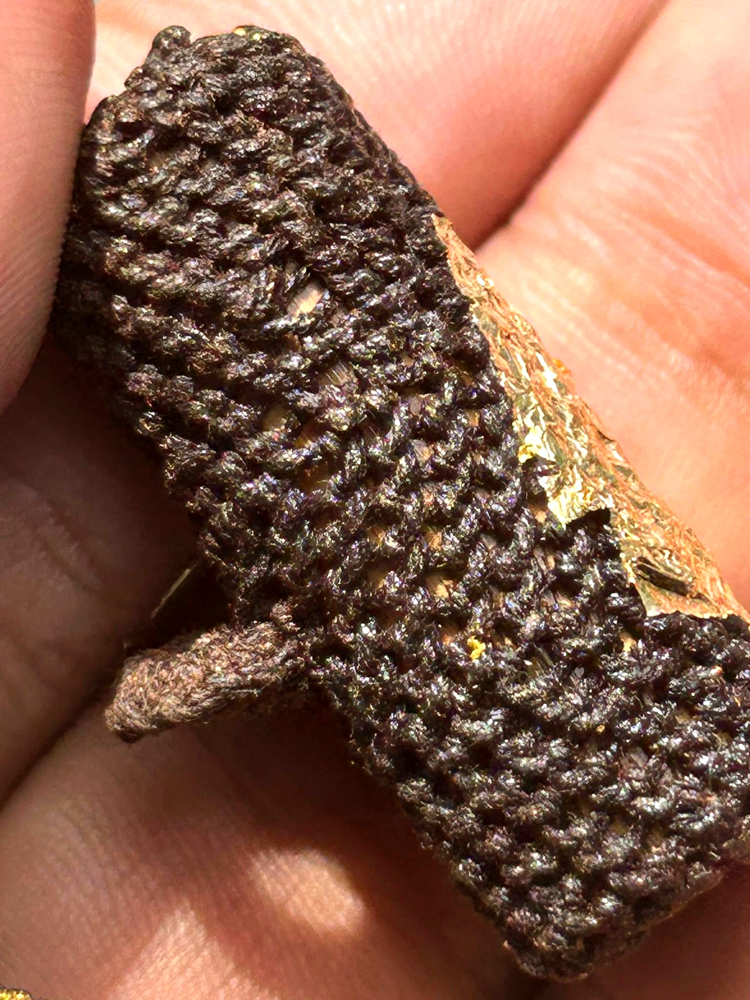 Handheld woven brown Takrut Phai Tan amulet for protection with gold leaf and braided cord texture