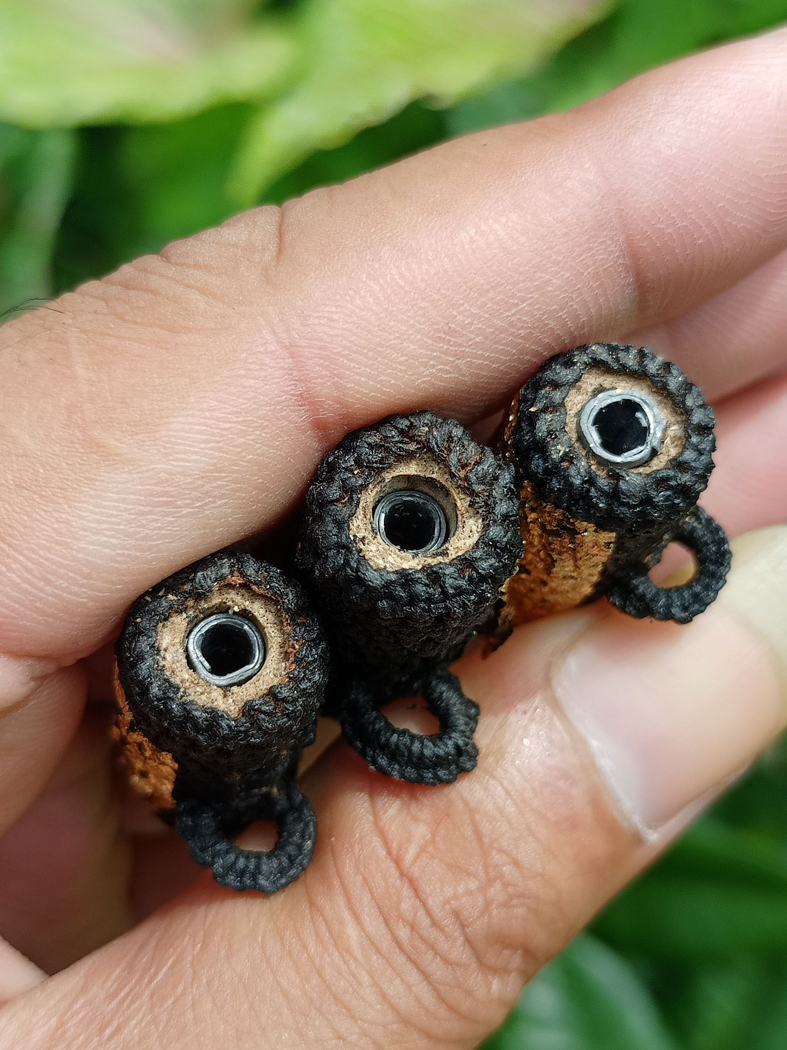 Takrut Phai Tan amulet for protection three hand held black wrapped cylindrical Thai amulets with metal cores