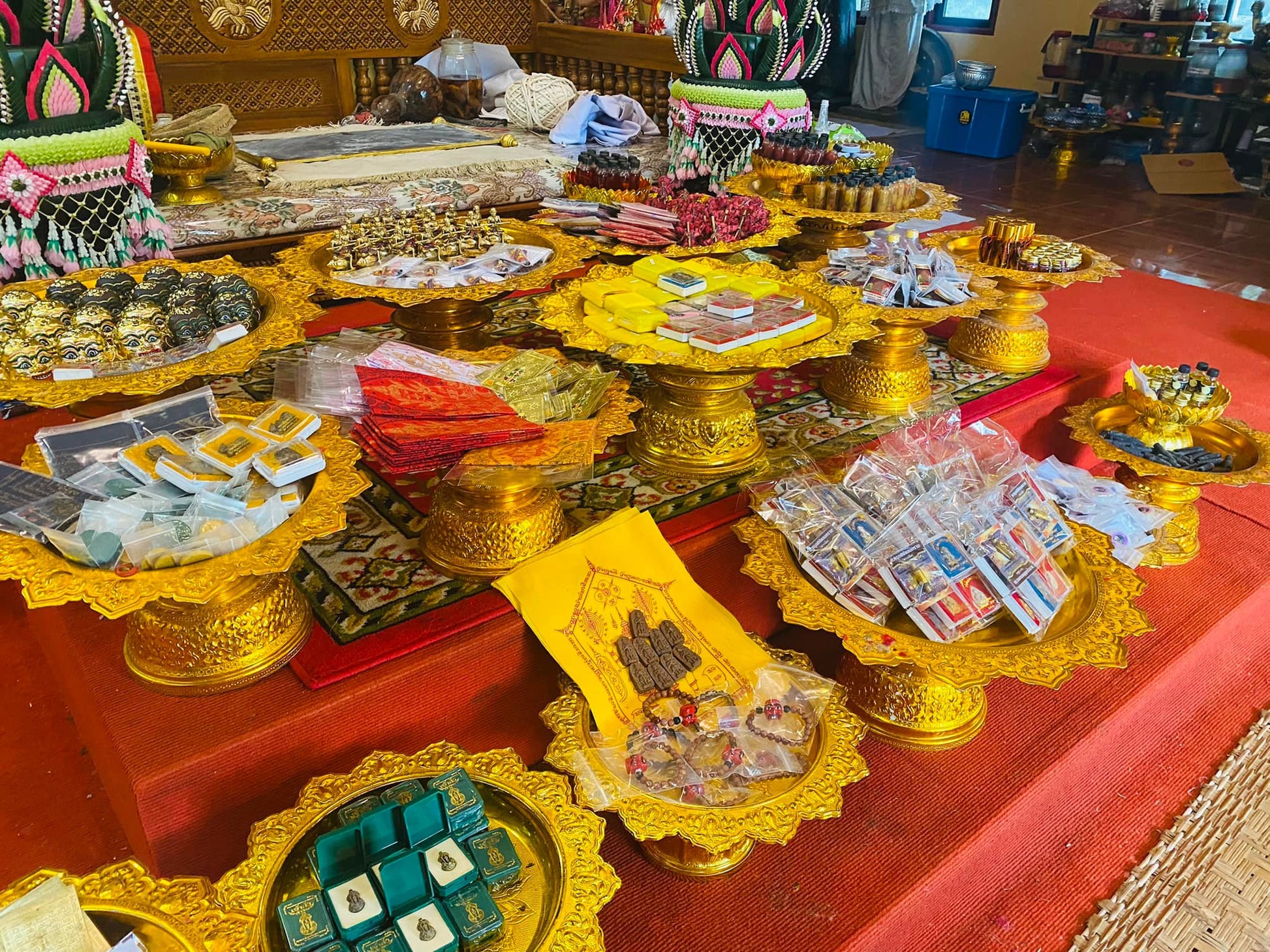 Assortment of Thai amulets and small bottles on golden trays on temple altar Thai Buddhist charm oil for loving kindness