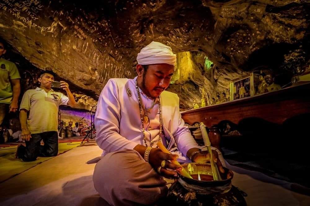 Thai monk preparing Thai Buddhist charm oil for loving kindness during cave blessing ritual